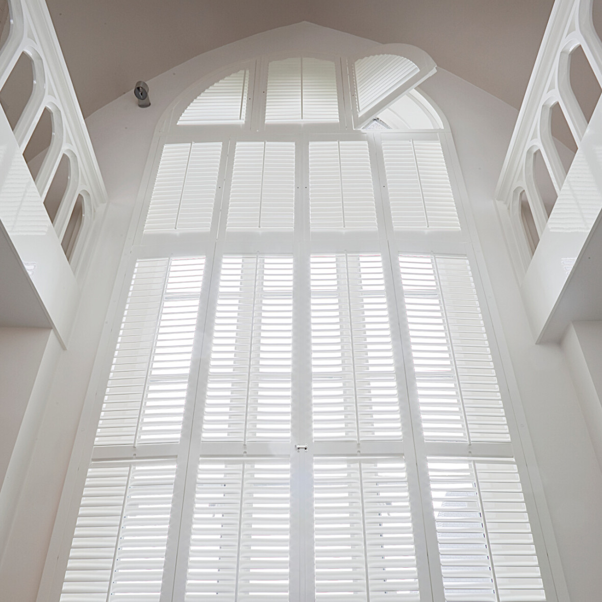 Witte shutters voor een hoog raam met een ronde vorm